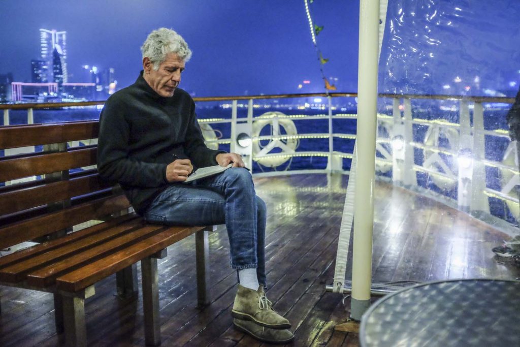 Photograph of Anthony Bourdain on Hong Kong Ferry writing in his journal. Courtesy of CNN